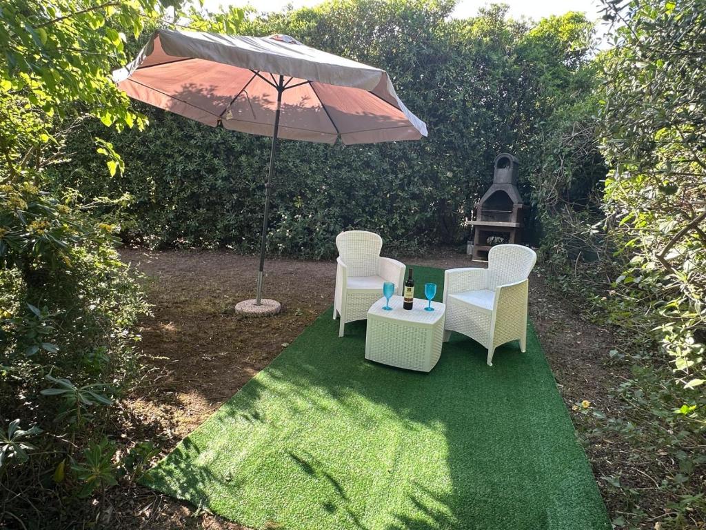 a patio with two chairs and an umbrella at Villetta il caminetto in Geremèas