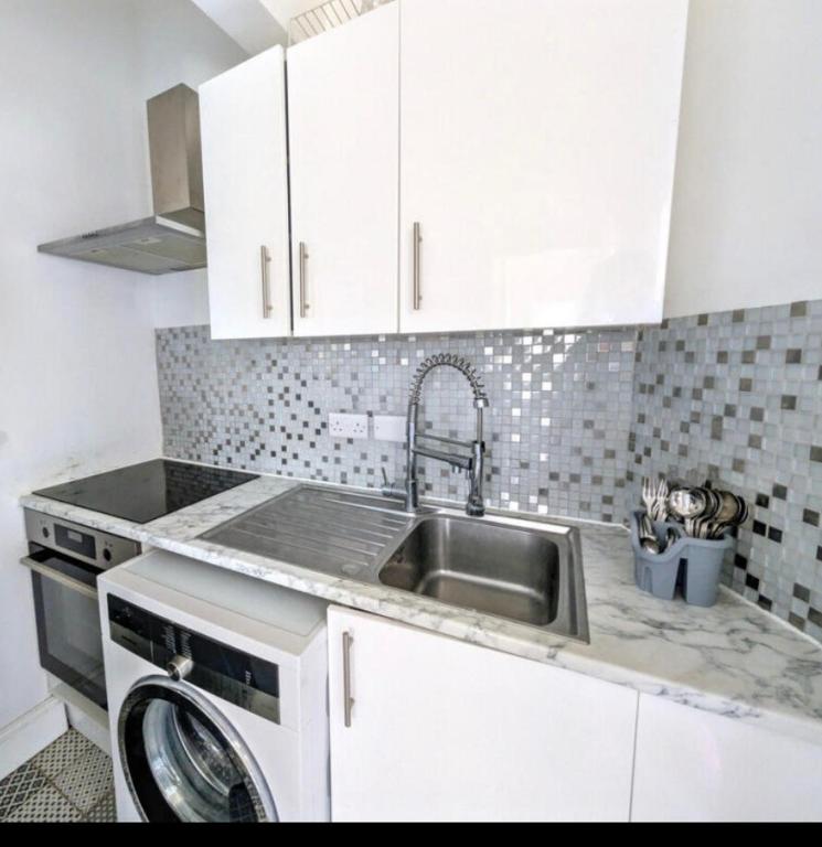 a kitchen with a sink and a dishwasher at Sunshine apartment in Maidstone