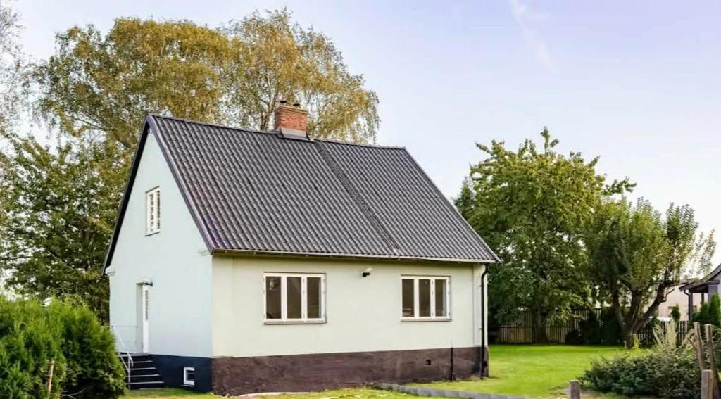 a white house with a black roof at The Green House Holiday Home in Tomelilla