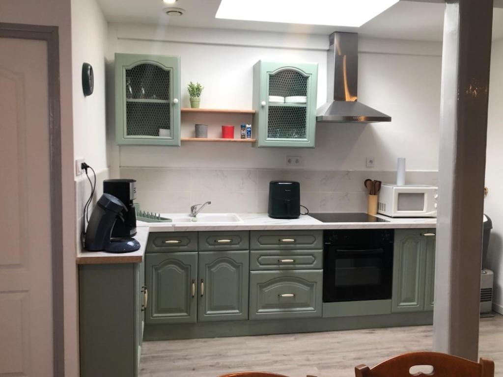 a kitchen with green cabinets and a sink at Mers in Mers-les-Bains