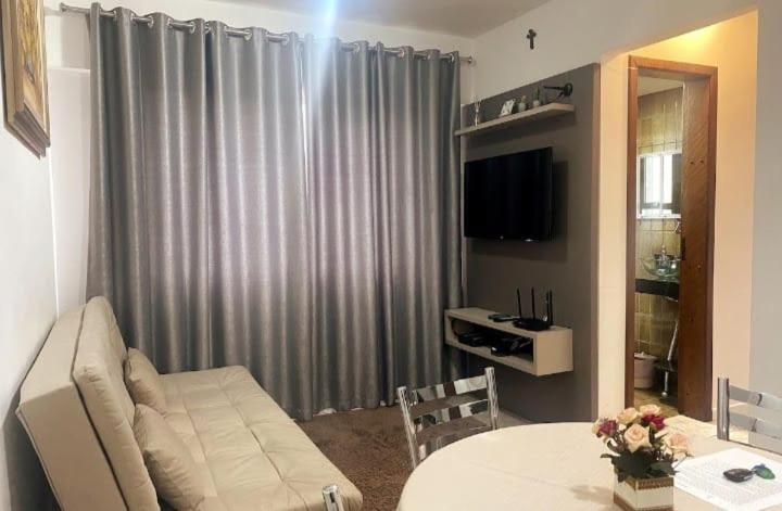 a living room with a couch and a table and a television at Loft aconchegante no Centro in Joinville