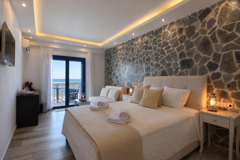 a bedroom with a large bed with a stone wall at Ocean View Rooms in Paralia Vrachou