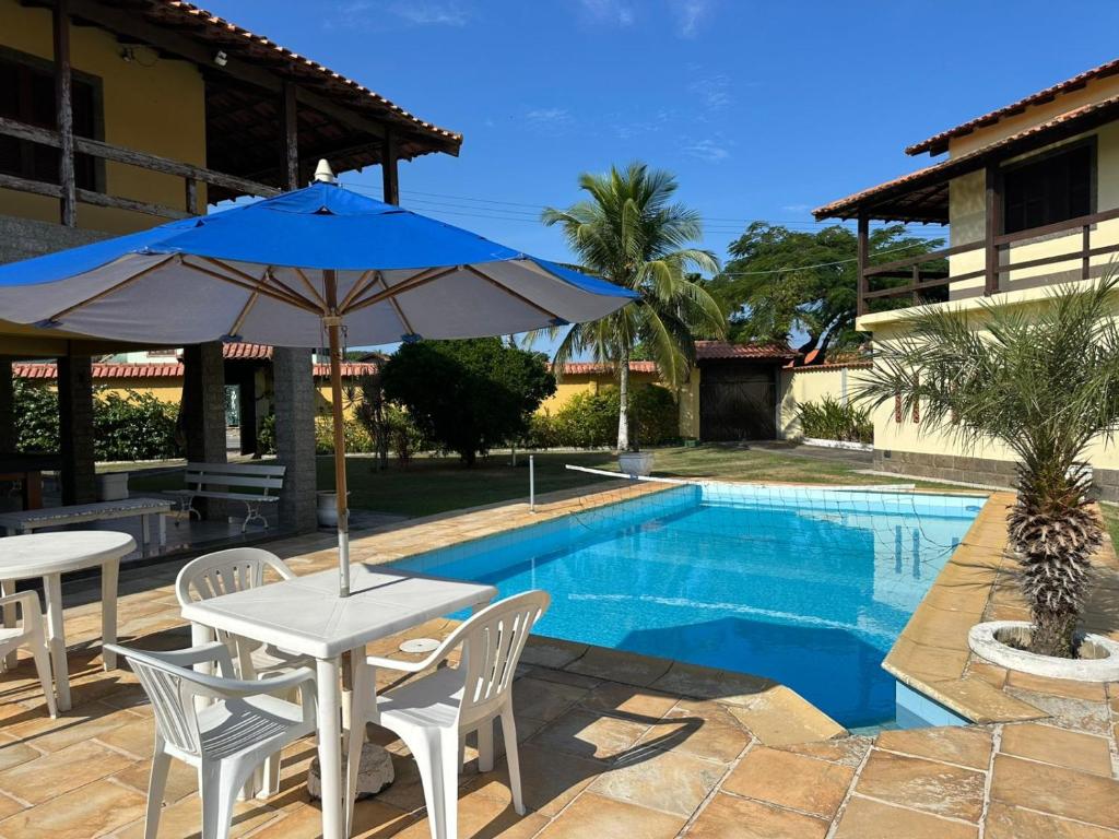 a table with an umbrella next to a swimming pool at Casa Bella Itaúna Suites in Saquarema
