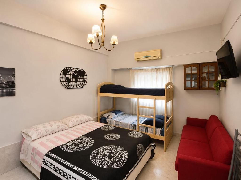 a bedroom with a bunk bed and a red couch at Monoambiente Ballester centro in Villa Ballester