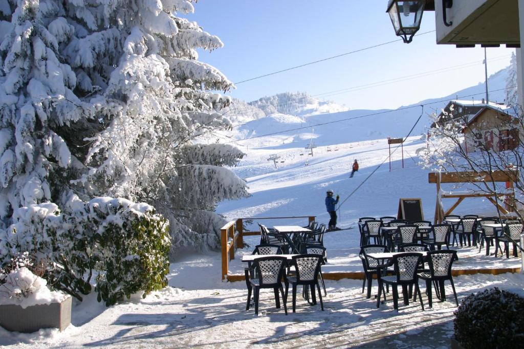 Un montón de mesas y sillas en la nieve. en Hôtel Le Christania, en Bellevaux