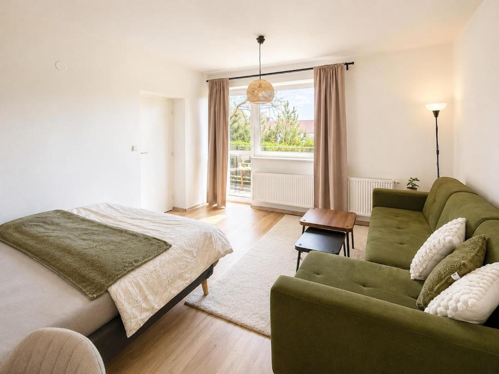a bedroom with a green couch and a bed at Moderní studio s terasou v klidné lokalitě in Jihlava