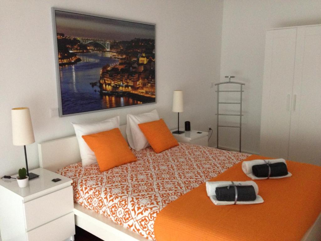 1 dormitorio con 1 cama con almohadas de color naranja y una pintura en la pared en AP da Baixa, en Oporto