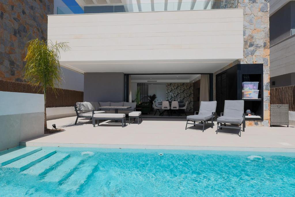 a swimming pool next to a house with a patio at Designer Villa with BBQ & Heated Pool on Santa Rosalia Lake Resort in Torre-Pacheco