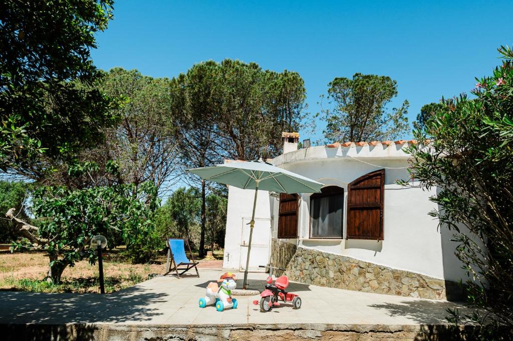 three dolls sitting under an umbrella in front of a house at Casa P - Relax nel verde a Ezzi Minori in Cuile Ezi Mannu