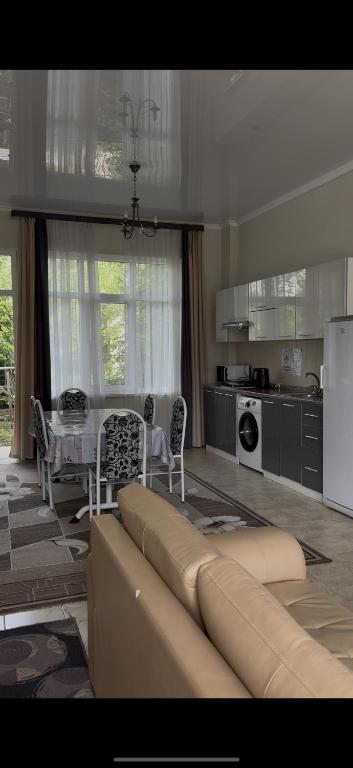 a living room with a couch in front of a kitchen at Танхаус Коттедж in Bosteri