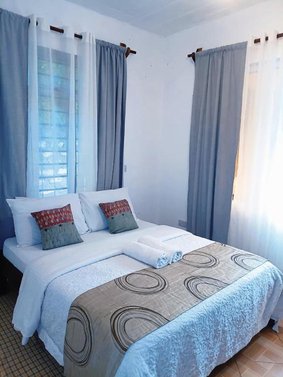 a bedroom with a large bed with blue curtains at Devkim Stays-Cozy Comfort Near The Beach in Ukunda
