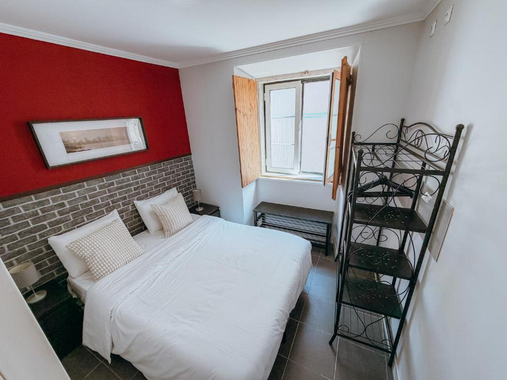 a bedroom with a white bed and a red wall at Aliciamar 29 by Casas de Setúbal in Setúbal