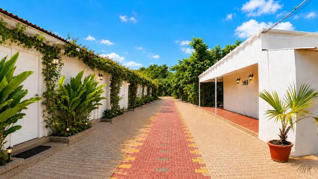 a brick road between two white buildings with plants at Gardens by Lotels in Madambakkam