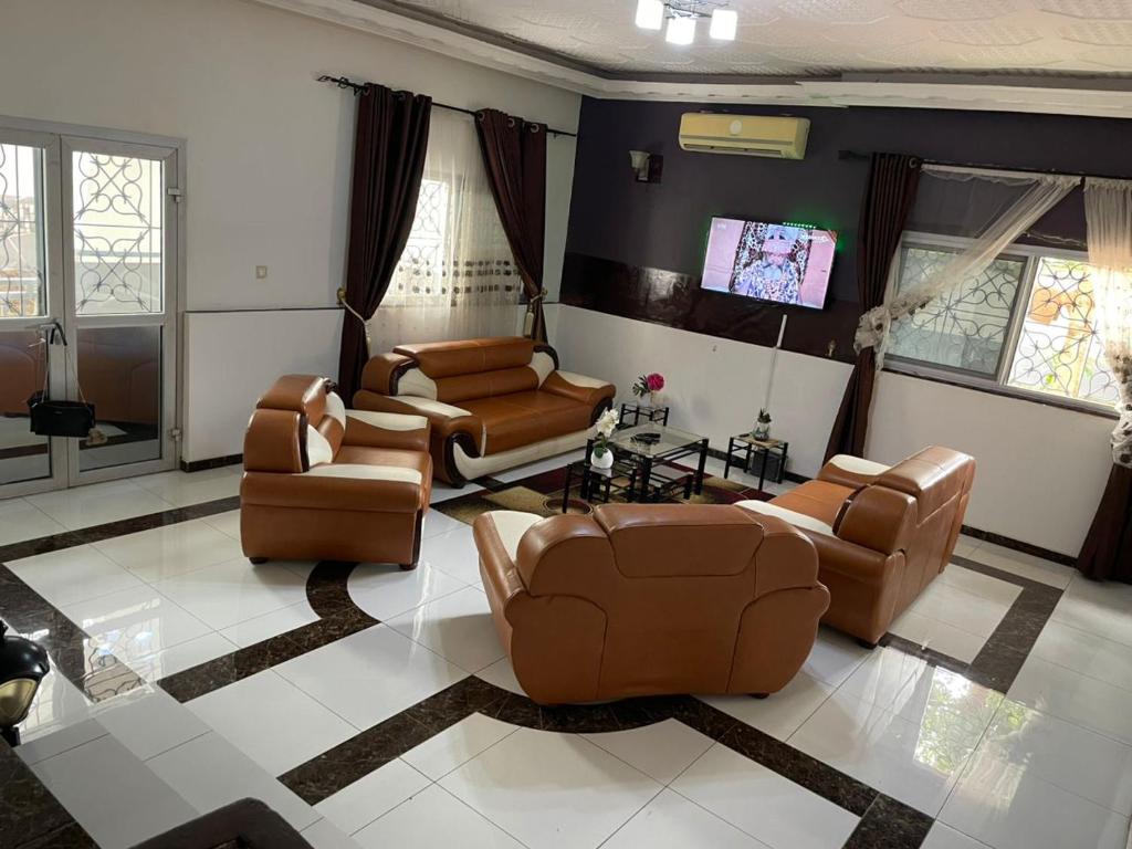 a living room with leather furniture and a flat screen tv at Villa le Dakota la différence in Yaoundé