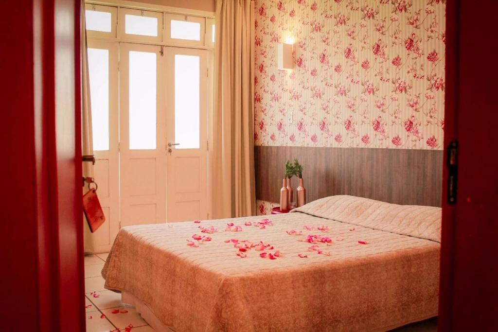 um quarto com uma cama com flores cor-de-rosa em Pousada Macamirim em Macaíba