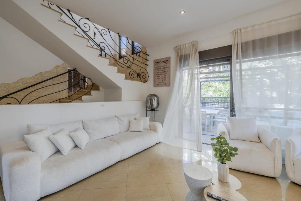 a living room with a white couch and a staircase at וילה הריביירה in Netanya