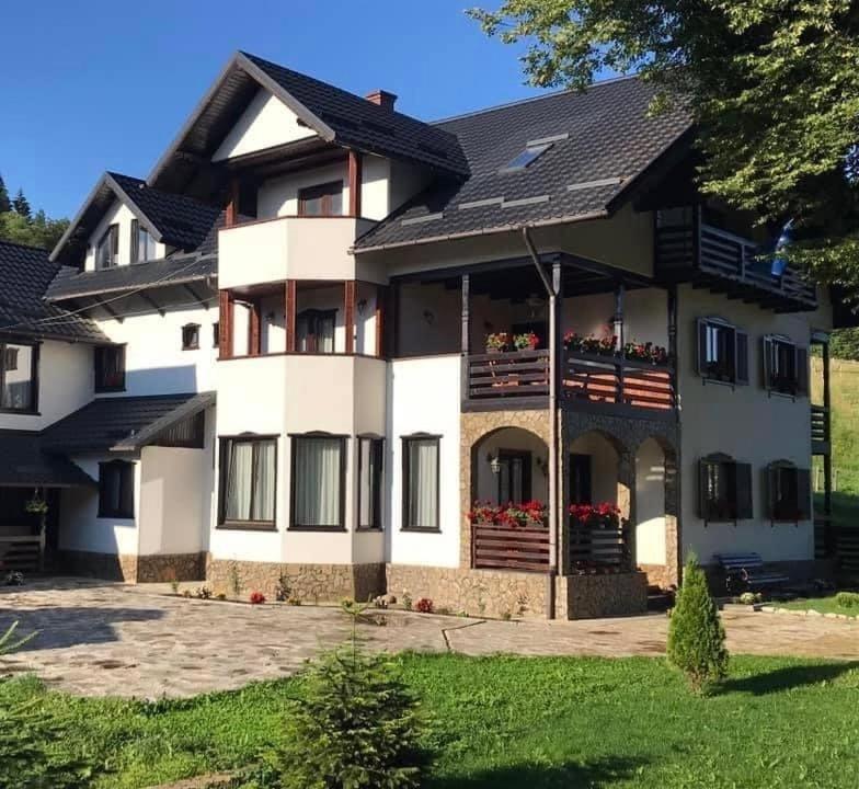 a large white house with people on the balconies at Casa Corlățeni in Pojorâta