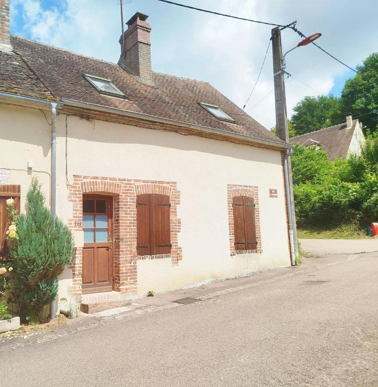 an old white house with brown doors and a street at Gîte Mézilles location sem-we in Mézilles