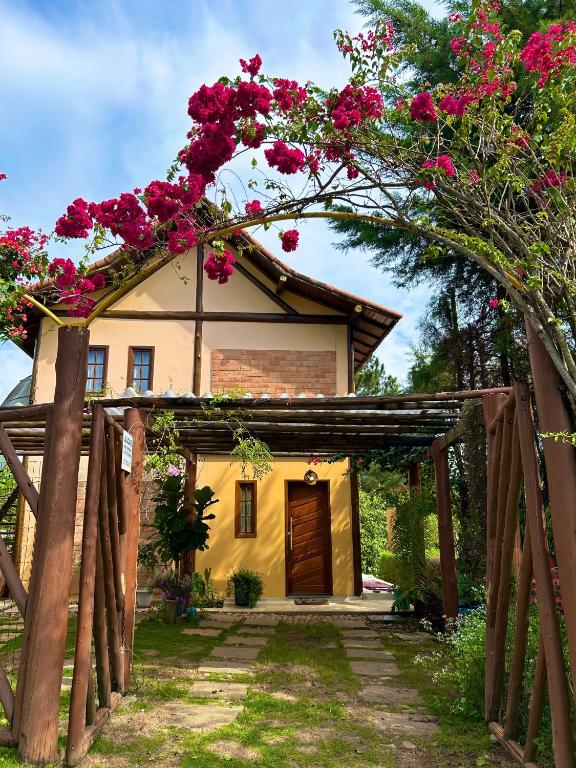 a house with pink flowers on top of it at Chalé no coração de Penedo - Pet Friendly in Itatiaia