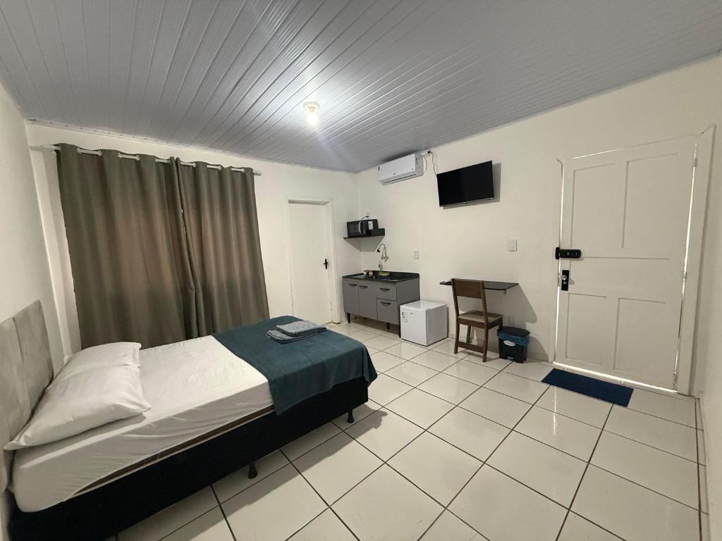 a bedroom with a bed and a desk in it at Flat a 3 minutos do centro de Chapecó in Chapecó