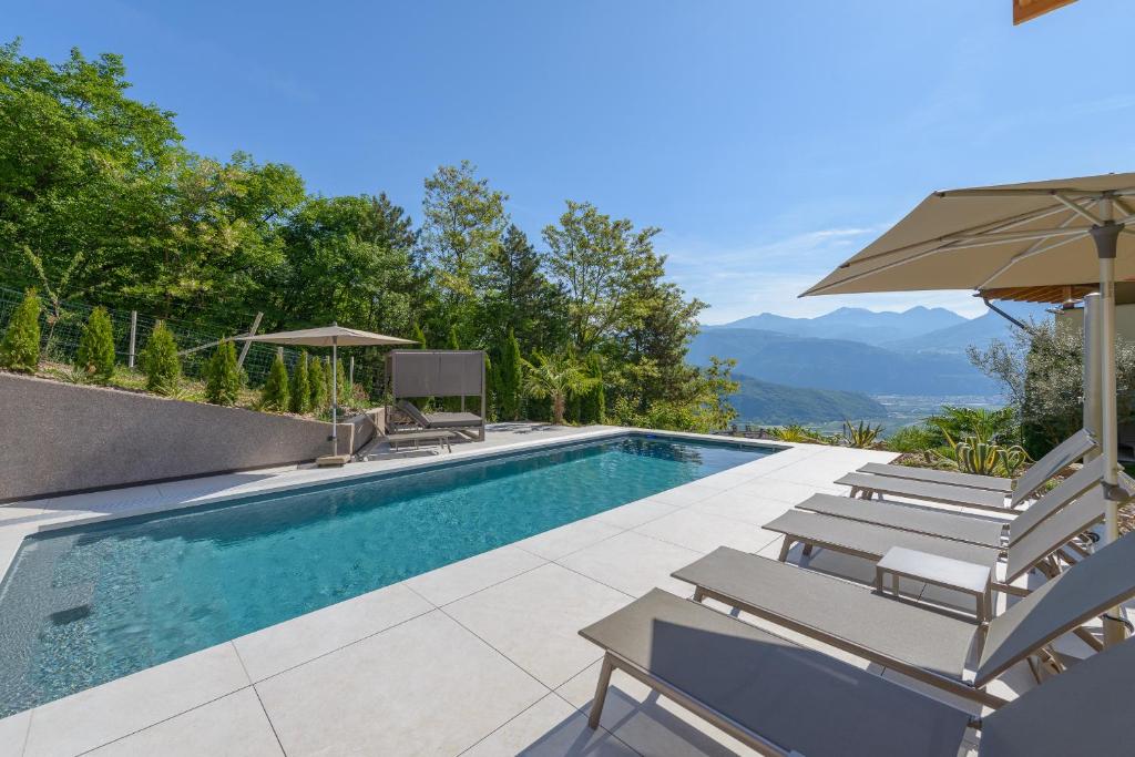 a swimming pool with chairs and an umbrella at Apfelhof in Termeno