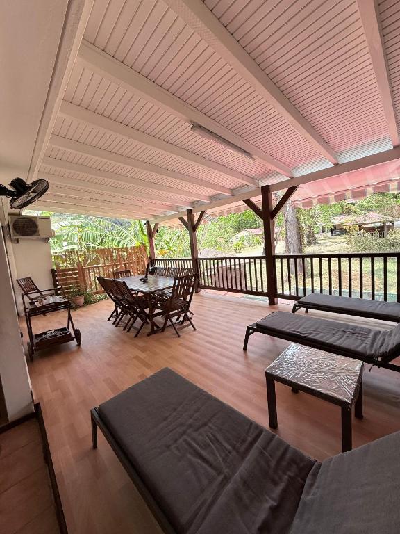 a screened porch with a table and chairs and a deck at Pépite Anses in Les Anses-dʼArlets