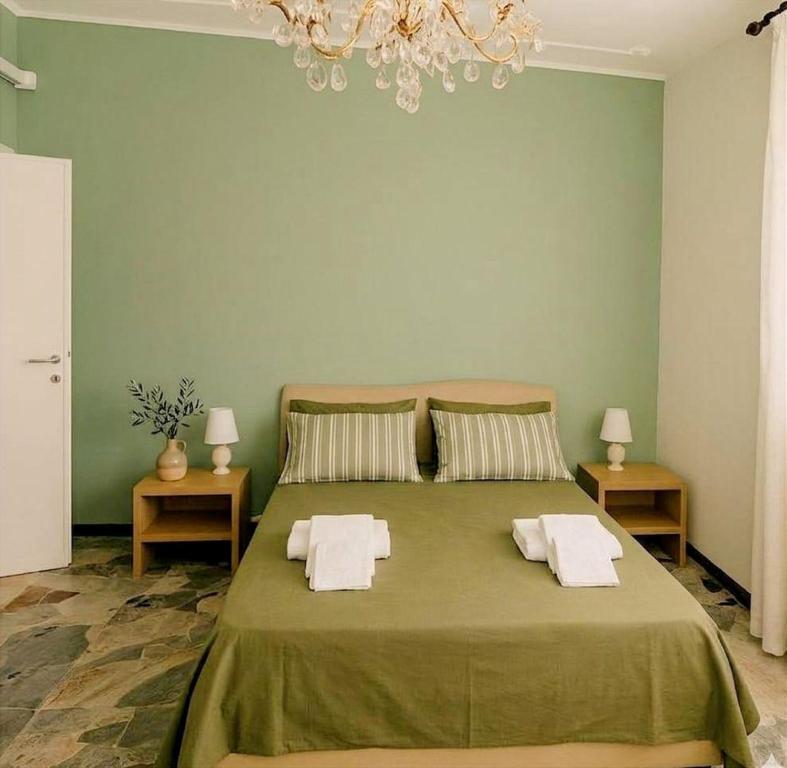 a green bedroom with a large bed with towels on it at Torres House Suite & Rooms in Sassari