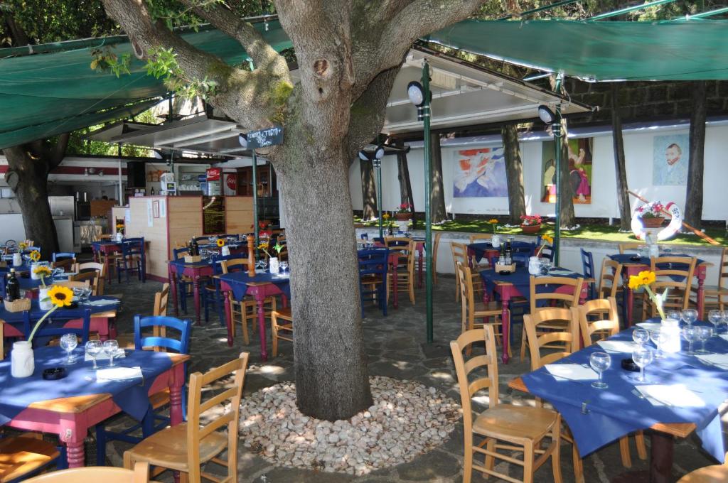 a restaurant with blue tables and chairs under a tree at Villa Tergeste in Trieste