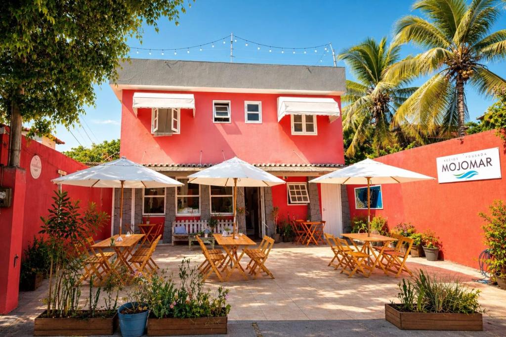 a restaurant with tables and umbrellas in front of a building at Pousada Mojomar Buzios in Búzios