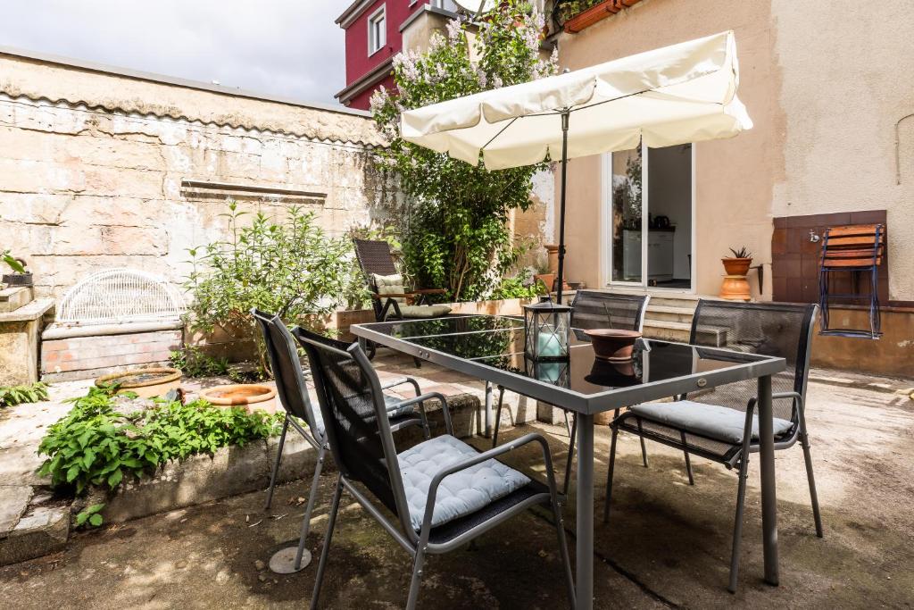 a glass table with chairs and an umbrella at Apartment in Bayreuth in Bayreuth