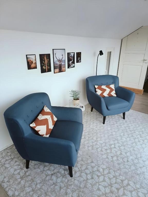 two blue chairs in a living room with pictures on the wall at Hegauzauber in Tengen