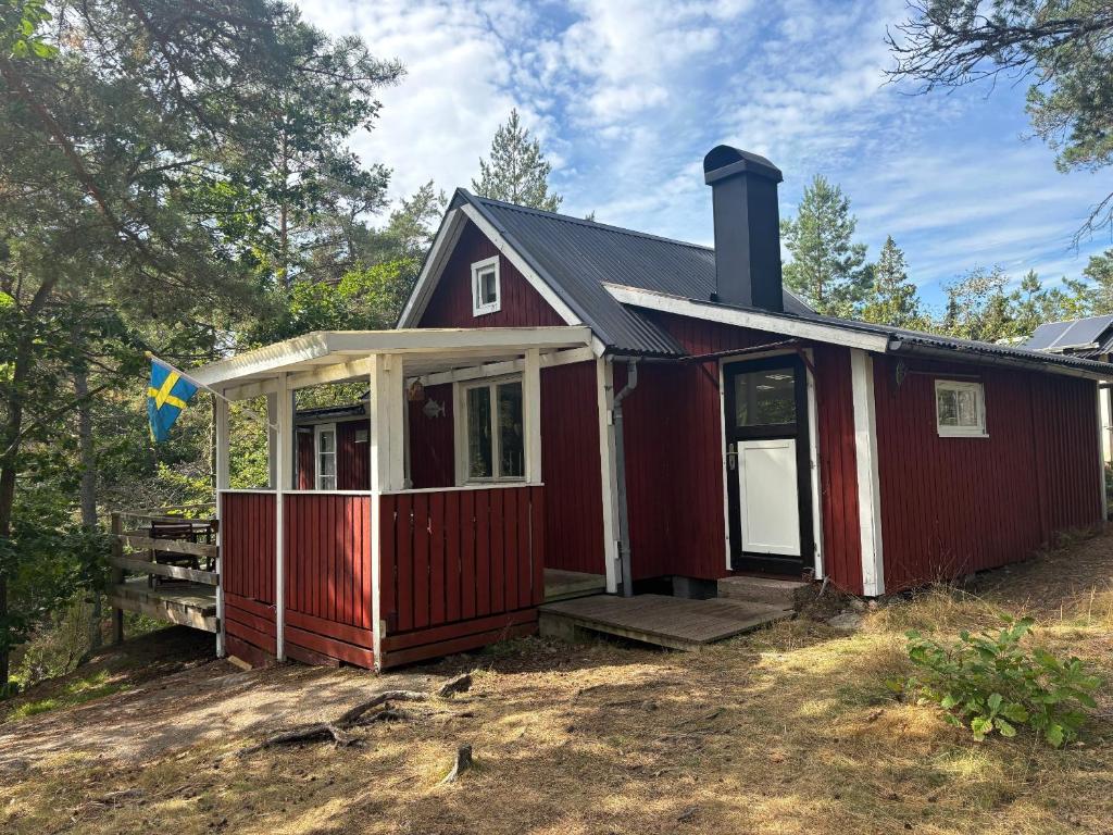 a red house with a front porch with trees at Hus Sinnermåla in Högsby