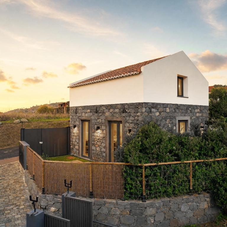 a stone house with a fence in front of it at Piu Bella in Fajã da Ovelha