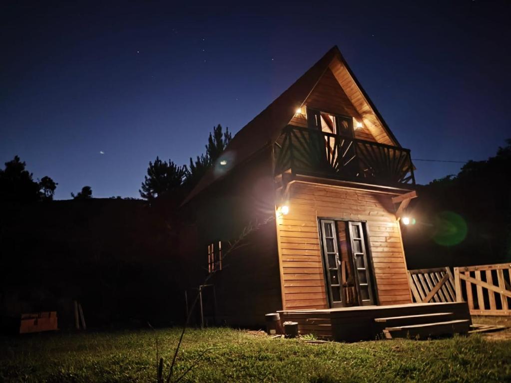 a small wooden house with lights on it at night at Chalé na Vila Do Sossego in Alfredo Wagner
