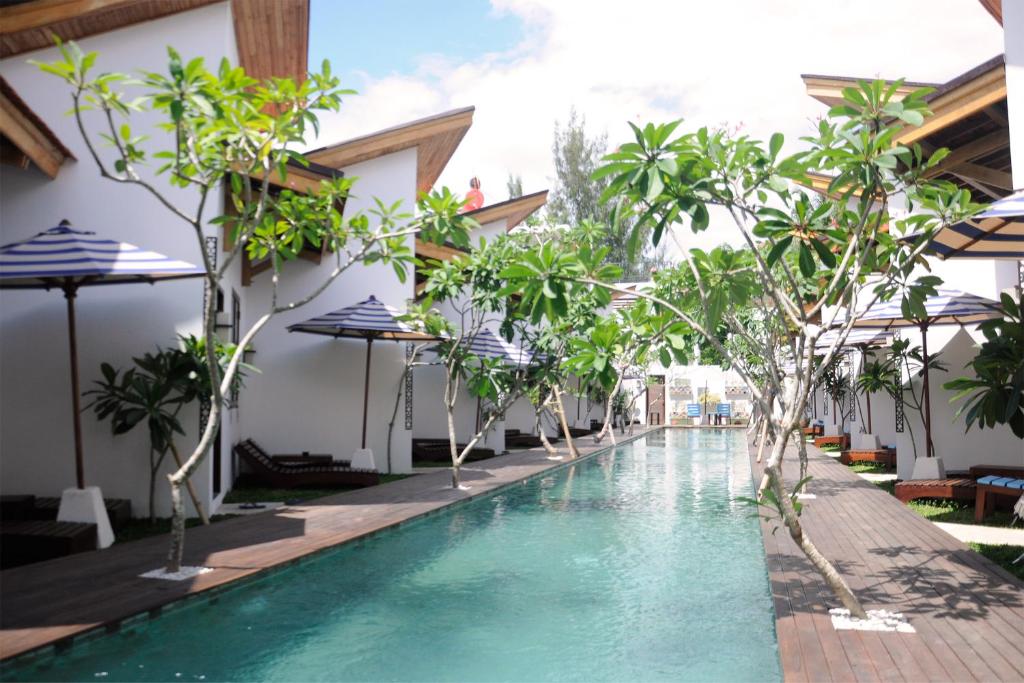 une piscine dans un complexe avec des arbres et des parasols dans l'établissement Jali Resort - Gili Trawangan, à Gili Trawangan