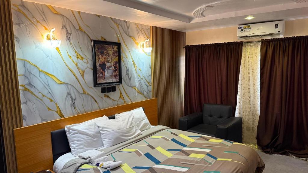 a hotel room with a bed and a chair at Dopad Hills Hotel and Suites in Ojo