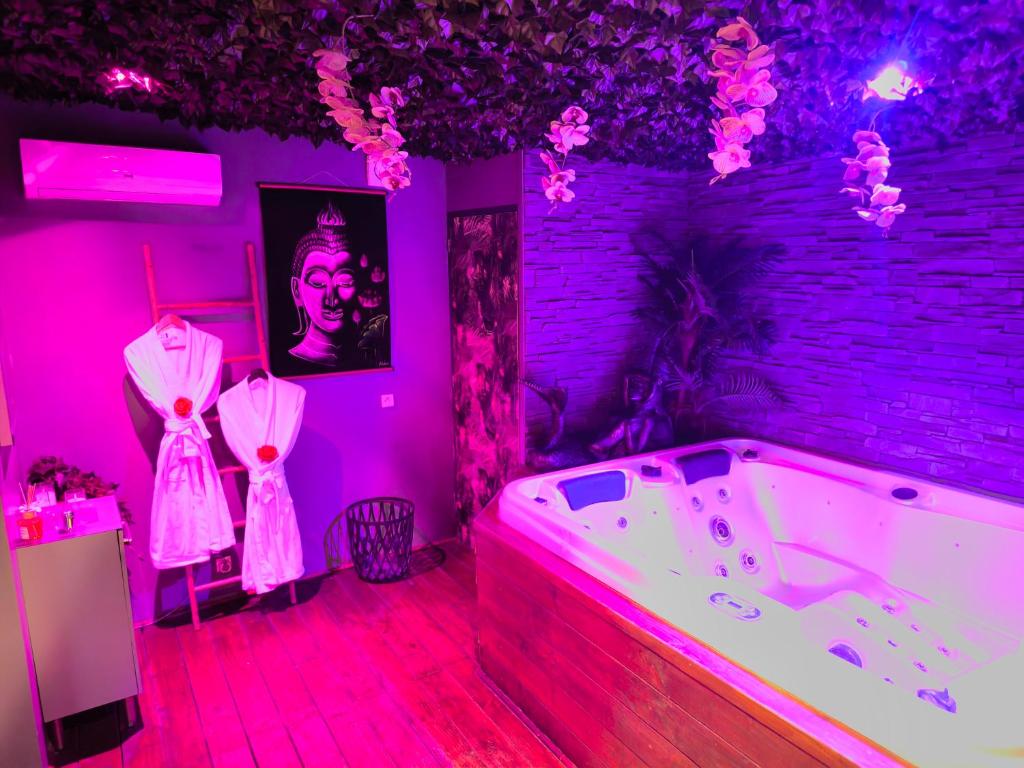 a purple room with a bath tub and pink lighting at L'instant secret in Berlaimont