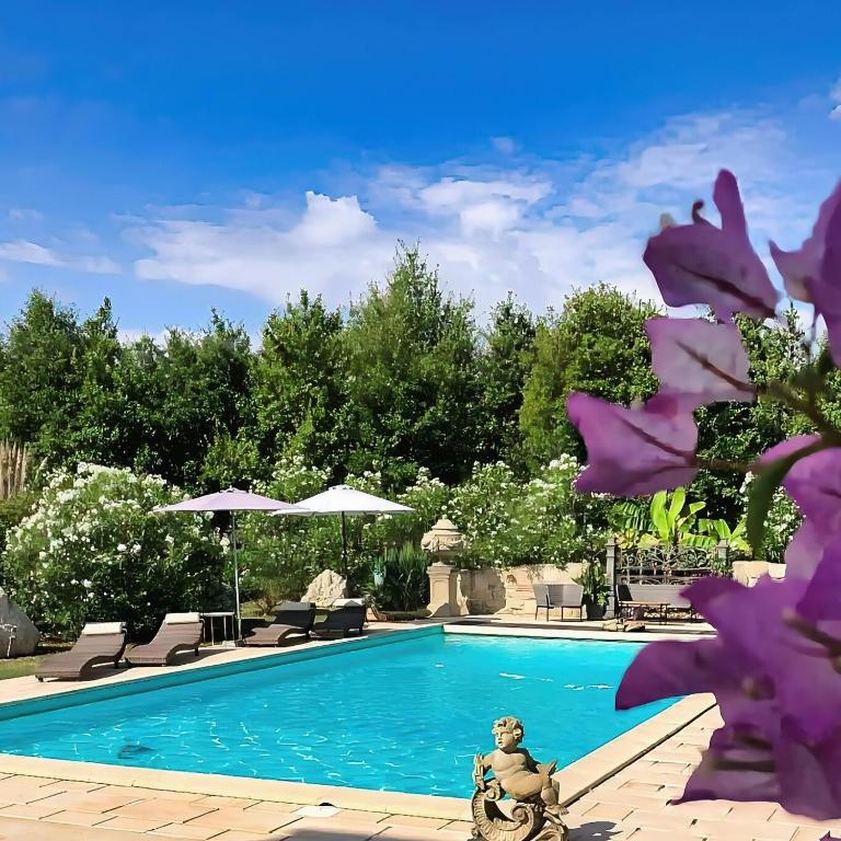 a swimming pool with purple flowers in front of it at En bord de rivière in Casseneuil