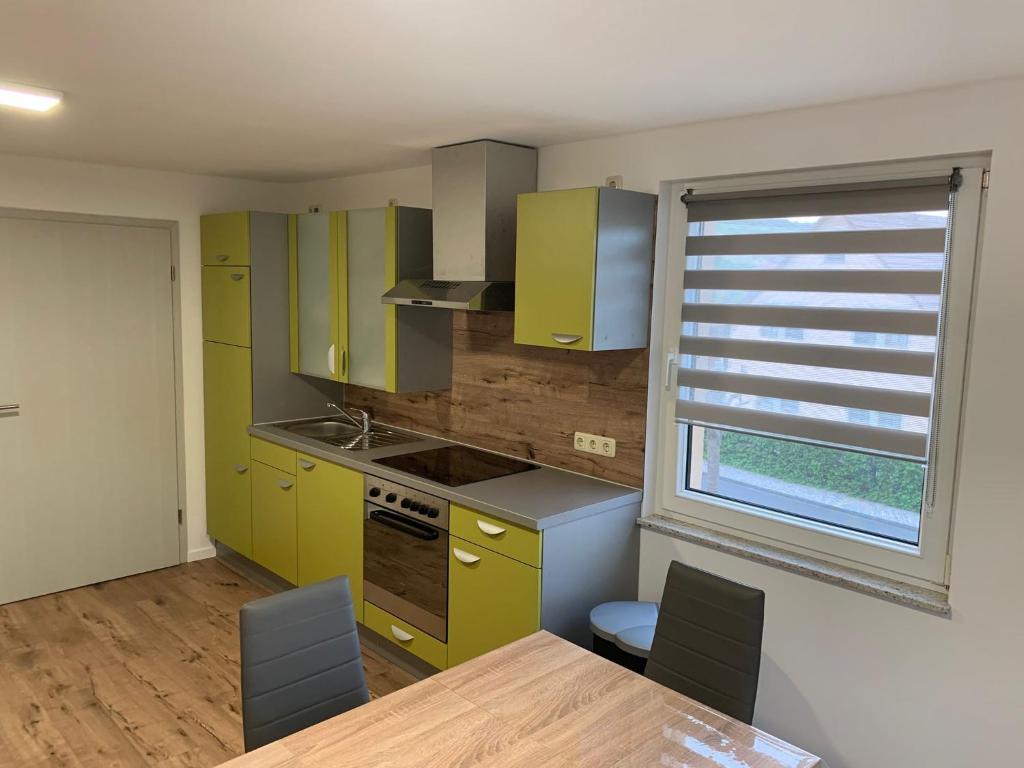 a kitchen with yellow cabinets and a table and a window at Ferienwohnung Ulsteraue in Geisa