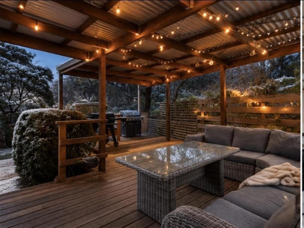 a patio with a couch and a table on a deck at The Cove - Lake Eildon in Piries