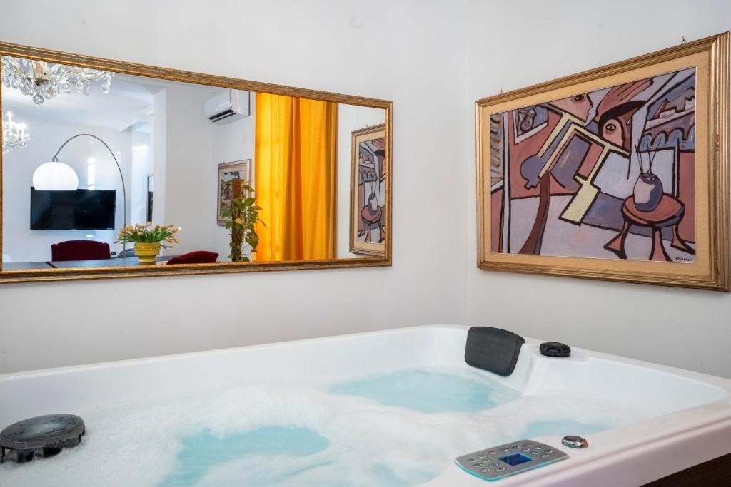 a bath tub with a mirror and a painting at Relais La Lanterne in Cagliari