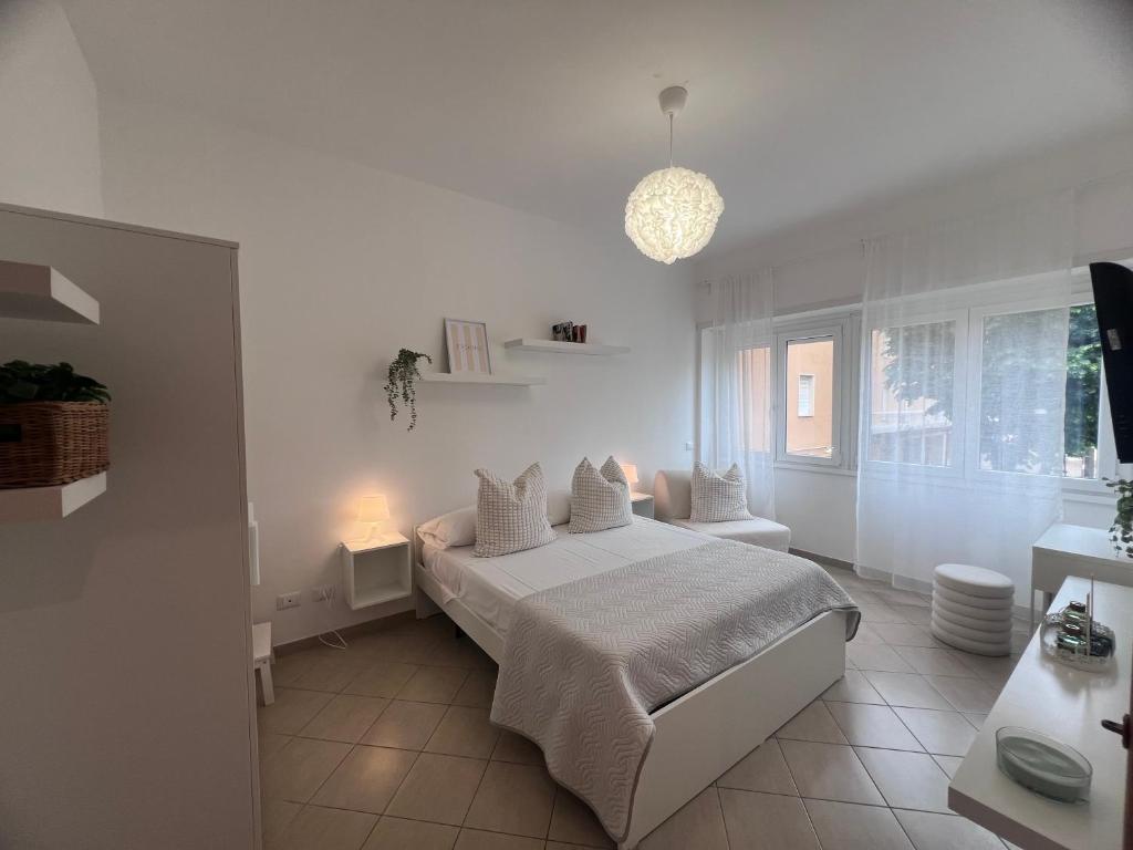 a white bedroom with a bed and a pendant light at TERRACINA Central Rooms in Terracina