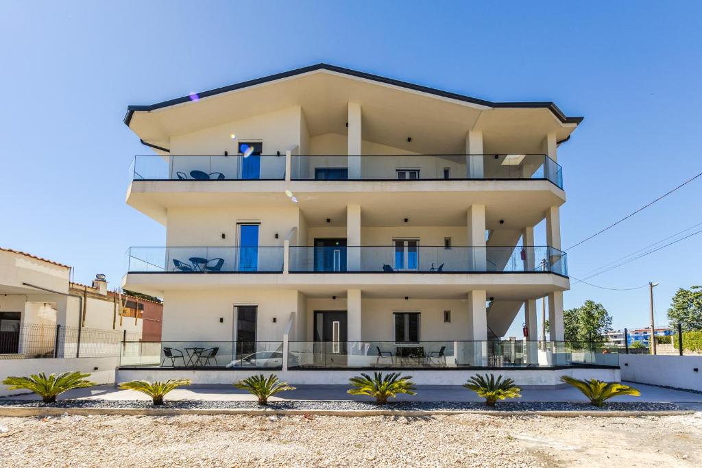 a large white building with blue balconies at Crystal Beach Rooms by PS in Durrës