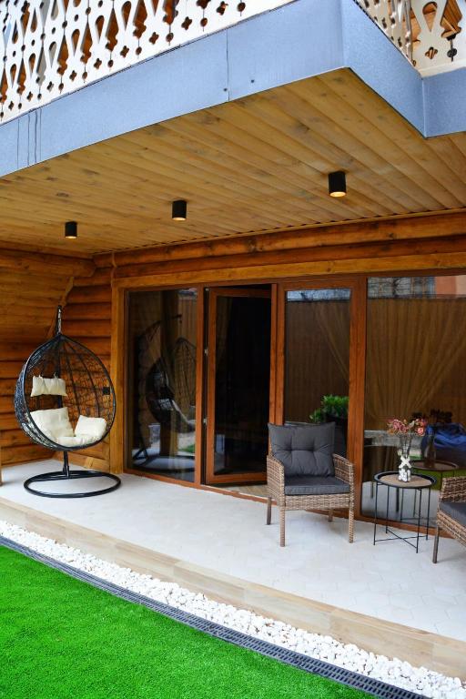 a house with a patio with chairs and a swing at Cottages Vakhrama in Abastumani