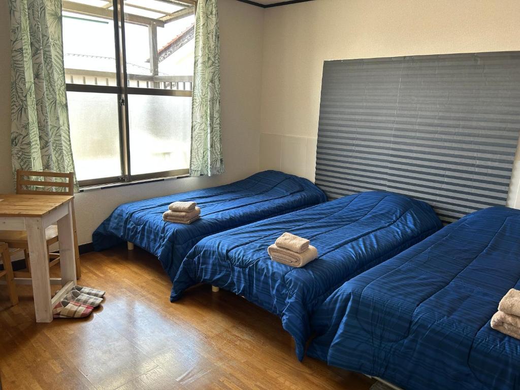 two beds in a room with blue sheets at なかじま宿 in Uenomachi