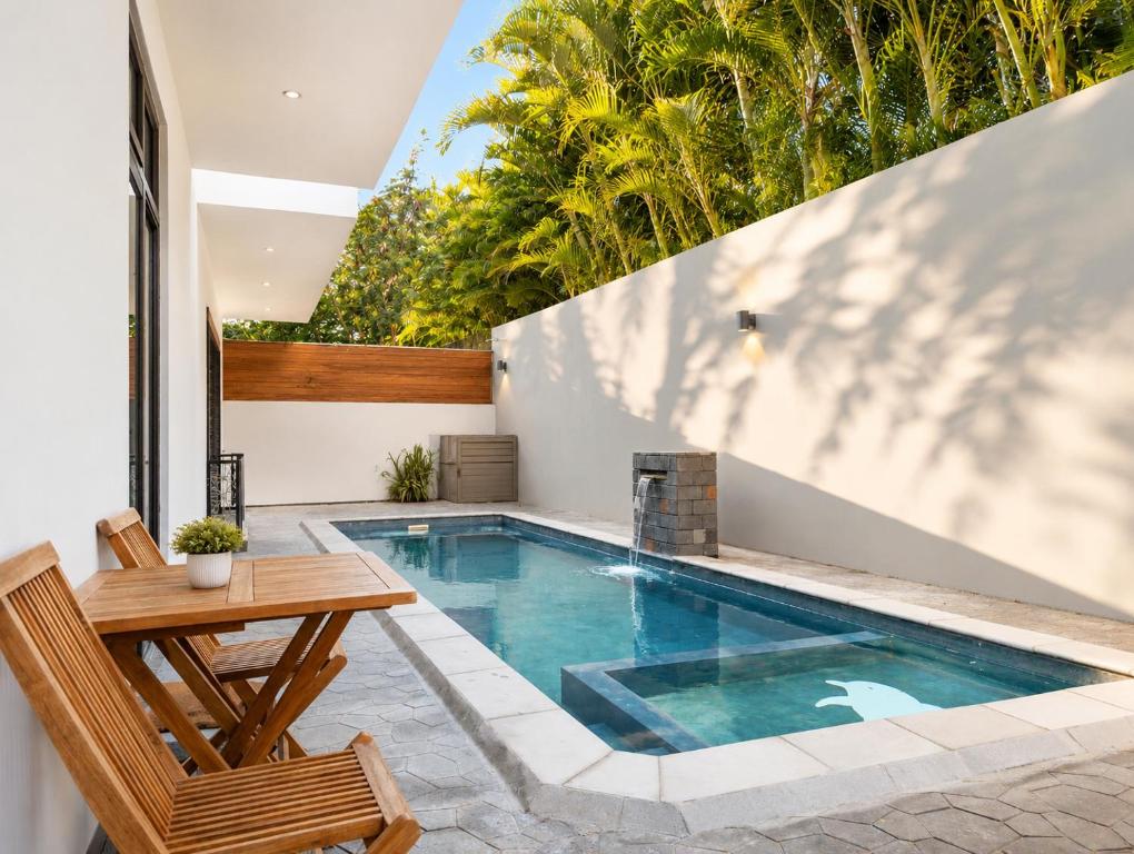 a swimming pool in a backyard with a wooden table and a wooden tablektop at Spacious Pereybere 3BR Apartment in Grand-Baie