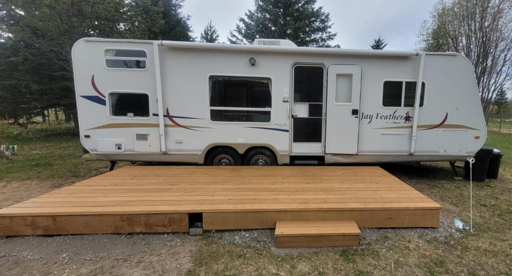 a white rv parked in a field with a wooden ramp at RV with Rocky Mountains View in McBride