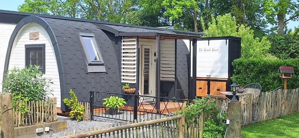a black shed with a fence in a yard at B&B De SluisPod in Hoogeveen