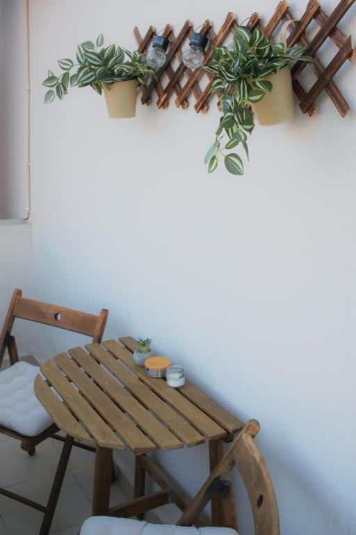 a wooden table and a chair with plants on a wall at Boho Center Studio in Keramoti