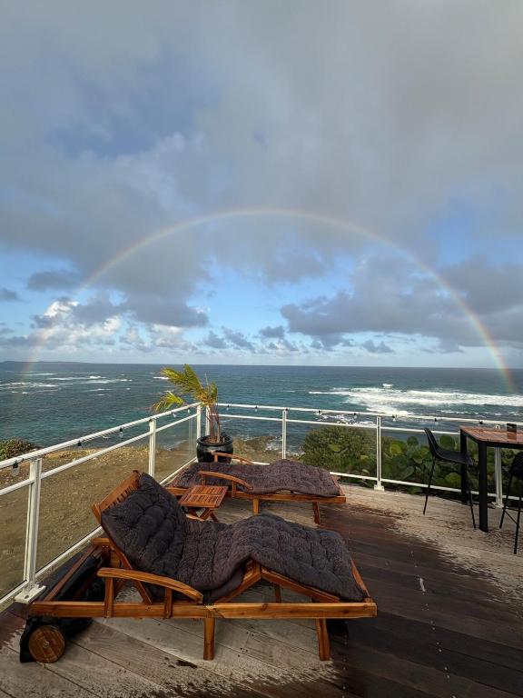 a rainbow over the ocean with two tables and chairs at Villa Dérimbeault in Oyster Pond
